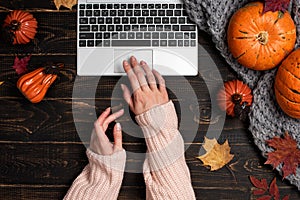 Female hands typing laptop on workspace with yellow and red maple leaves