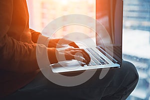 Female hands typing on laptop, young woman sitting next to window