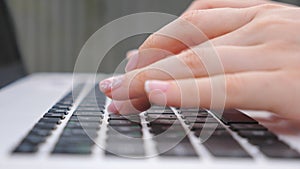 Female hands typing some text on keyboard of notebook. Unrecognizable woman working at laptop outdoor. Girl chatting