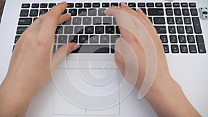 Female hands typing some text on keyboard of notebook. Woman sitting on her workplace and working at laptop. Girl