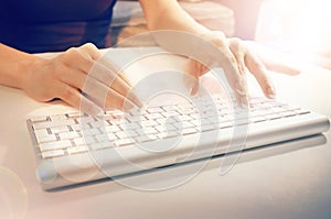 Female hands typing on a white computer keyboard