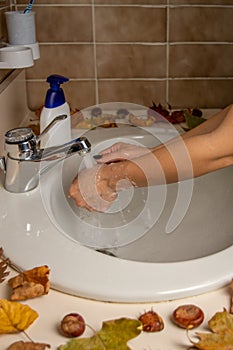 Female hands under the water jet from a circular sink