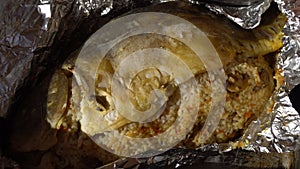 Female hands unfolding of baked fish in foil