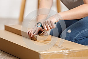 Female hands unpack a cardboard box with scissors. Open the parcel at home