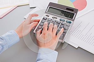 Female hands using calculator while working with documents.