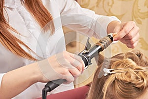 Female hands using curling iron.