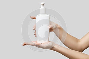 Female hands using hand sanitizer gel or liquid soap dispenser over light grey background