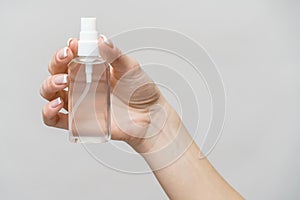 Female hands using hand sanitizer spray dispenser over light grey background