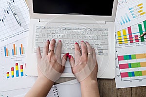 Female hands using laptop with business graphs.