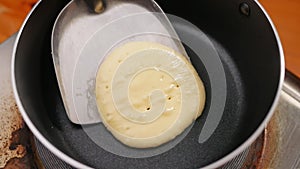 Female hands using a spatula to fliping over pancakes on a hot pan.