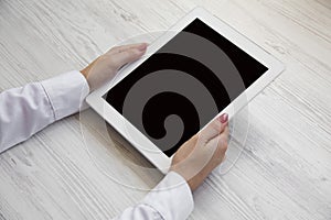 Female hands using tablet on a white wooden background