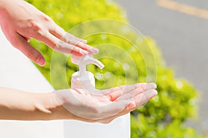 Female hands using wash hand sanitizer gel pump dispenser.