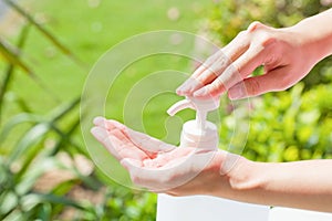 Female hands using wash hand sanitizer gel pump dispenser.