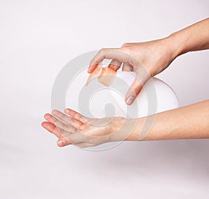 Female hands using wash hand sanitizer gel pump dispenser