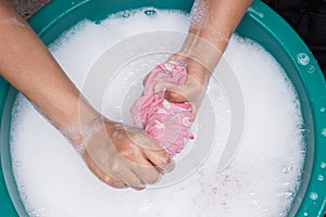 Female hands wash clothing by hand with detergent in basin. selective focus and space for text