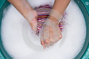 Female hands wash clothing by hand with detergent in basin. selective focus and space for text