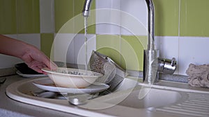 Female Hands Wash Dirty Plates in Kitchen Sink Under Running Water. 4K