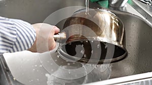 Female hands wash a plastic cutting board in the kitchen. Metal pan in the sink. House cleaning and cleanliness