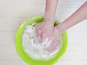 Female hands washing laundry in a basin on a wooden background