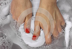 Female hands washing white clothes in basin