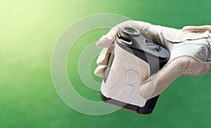 Female hands wearing professional glove with white and black modern optical range finder used for golfing or hunting