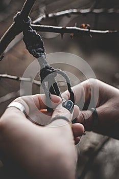 Female hands weaving a macrame braid on a tree