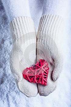 Una donna mani bianco lavorato a maglia guanti intrecciate antico cuore rosso sul la neve. un San Valentino 