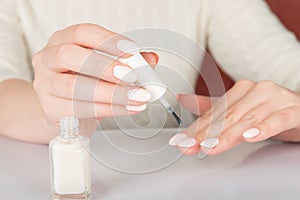 female hands with white nail varnish bottles