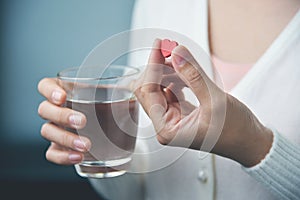 Female hands with white shirt is holding red pill in heart shape