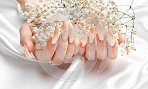 Female Hands on a white silk background with beautiful pearl manicure.Hands on a brown background and beautiful pearl manicure