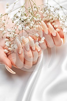 Female Hands on a white silk background with beautiful pearl manicure.Hands on a brown background and beautiful pearl manicure