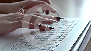 Female hands of a woman typing on a laptop keyboard while sitting at her desk