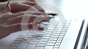 Female hands of a woman typing on a laptop keyboard while sitting at her desk