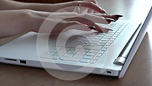 Female hands of a woman typing on a laptop keyboard while sitting at her desk
