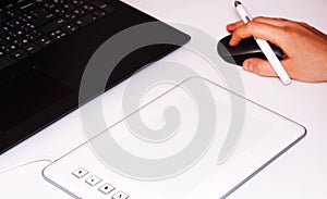 Female hands work on a graphic tablet. Hand holds stylus pen and draws. White graphic tablet. The work of a graphic designer. Girl