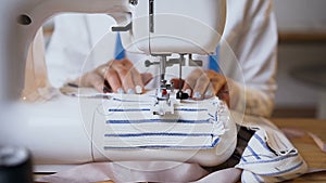 Female hands working on sewing machine.