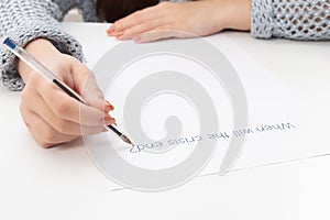 Female hands write on a piece of paper when the crisis is over