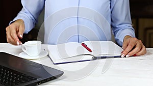 Female hands write to do list on blank notepad, drink coffee. Close up business lady hand writing company profit in her notebook.