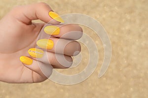 Female hands with yellow nail design. Yellow nail polish manicure. Woman hand on beige background copy space