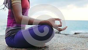 Female hands during yoga meditation in lotus pose on sea coast close up
