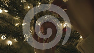 Female hanging christmas ball on tree at night