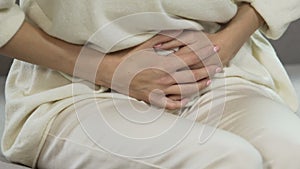 Female having stomach pain, period suffering, pregnancy problem, hands closeup