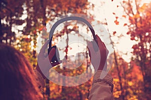 Female with headphones walking on the park listen sounds or music of autumn forest. Concept. Indian summer