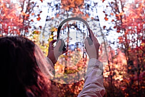 Female with headphones walking on the park listen sounds or music of autumn forest. Concept. Indian summer