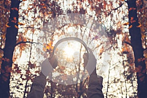 Female with headphones walking on the park listen sounds or music of autumn forest. Concept. Indian summer season