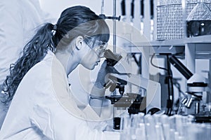 Female health care researcher microscoping in scientific laboratory.