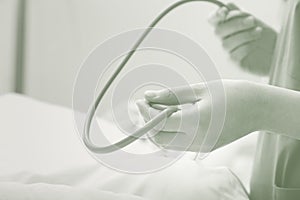 Female health worker holds phonendoscope at the patient bedside