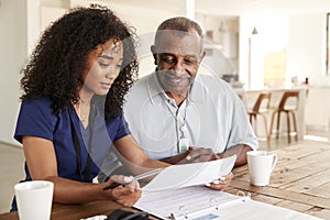 Female healthcare worker checking test results with a senior man during a home health visit