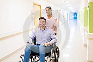Female Healthcare Worker With Patient On Wheelchair At Hospital