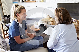 Female healthcare worker sitting on the sofa with a middle aged woman during a home health visit